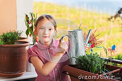 Adorable little girl watering plants on the balcony Stock Photo