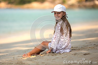 Adorable little girl at white beach during summer vacation,Cute little girl sitting alone on the beach looking at the sea,Travel Stock Photo