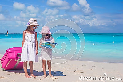 Adorable little girls walking big suitcase and map searching the way on tropical beach Stock Photo