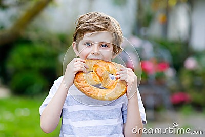 Adorable little kid boy eating huge big bavarian german pretzel. Stock Photo