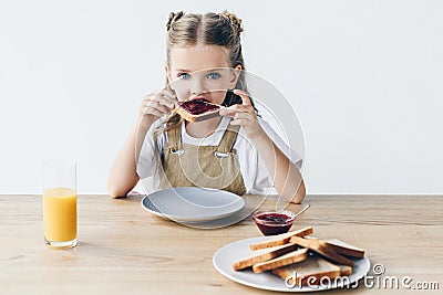 adorable little schoolgirl eating toast with jam Stock Photo