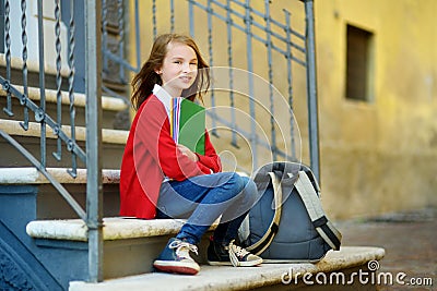 Adorable little schoolgirl studying outdoors on bright autumn day. Young student doing her homework. Education for small kids. Stock Photo