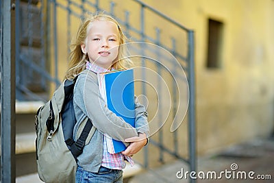 Adorable little schoolgirl studying outdoors on bright autumn day. Young student doing her homework. Education for small kids. Stock Photo