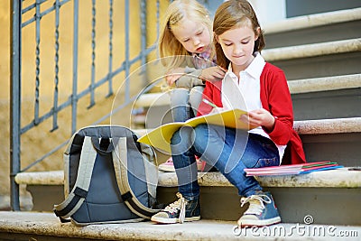 Adorable little schoolgirls studying outdoors on bright autumn day. Young students doing their homework. Education for small kids. Stock Photo