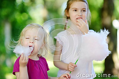 Adorable little sisters eating candy-floss Stock Photo