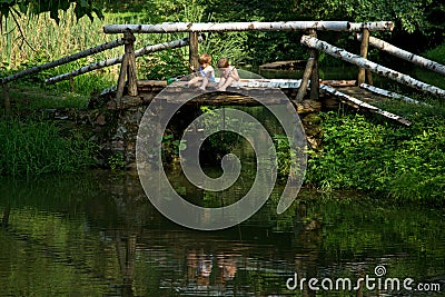 Adorable Little Twin Brothers Sitting on the Edge of Wooden Bridge and Fishing on Beautiful Lake Stock Photo