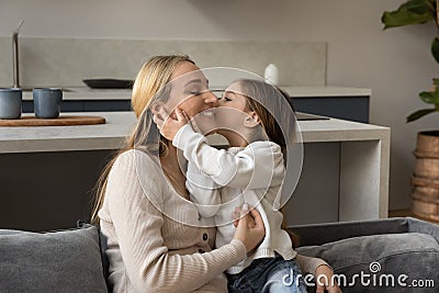 Adorable loving girl kissing happy smiling mom with love, gratitude Stock Photo