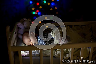 Adorable newborn baby boy, sleeping in crib at night Stock Photo