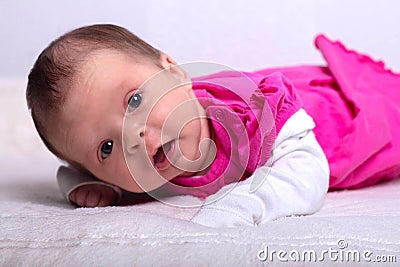 Adorable one month old baby girl in pink dress lies on a soft blanket Stock Photo