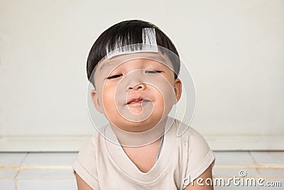 Adorable plump boy smilingly with chubby cheeked and close eyes. Front view of kid with illness Stock Photo