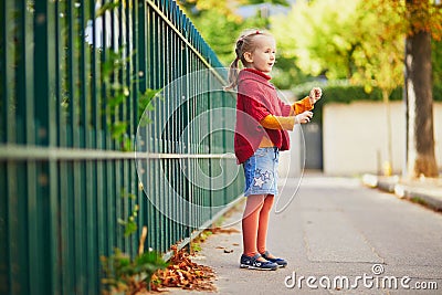 Adorable preschooler girl having fun on a street on a fall day Stock Photo