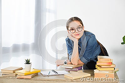 adorable preteen child resting chin on hand at table with books Stock Photo