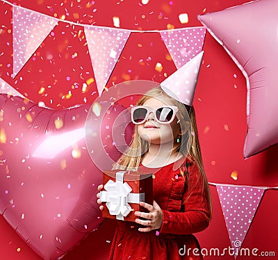 Adorable pretty girl with pink balloons and red present gift and birthday cap Stock Photo