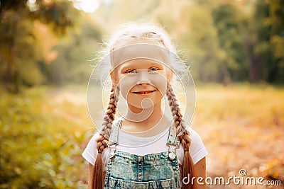 Adorable smiling little blonde girl with braided hair. Cute child having fun on a sunny summer day outdoor. Stock Photo