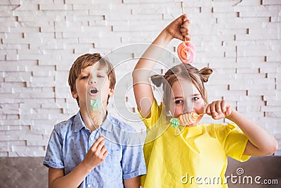 Adorable girl and boy holding colorful sweet meringues on a stick on Easter day Stock Photo