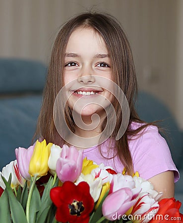 Adorable smiling little girl with tulips, close up, indoor Stock Photo