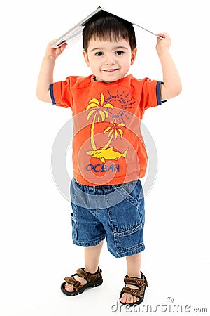 Adorable Toddler Boy With Book On Head Stock Photo