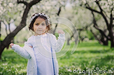 Adorable toddler child girl in light blue dressy outfit walking and playing in blooming spring garden Stock Photo