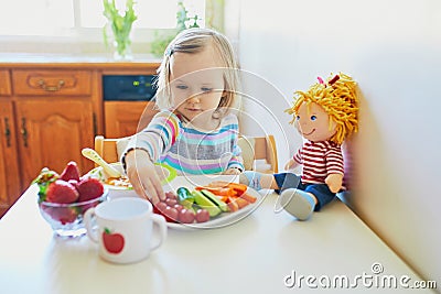 Adorable toddler girl eating fresh fruits and vegetables for lunch Stock Photo