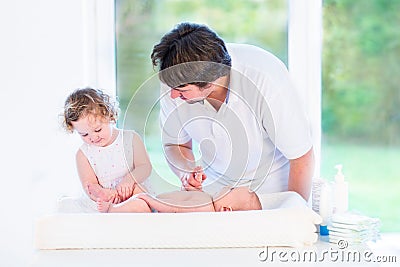 Adorable toddler girl helping father to change diaper Stock Photo