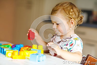 Adorable toddler girl playing with educational toys in nursery. Happy healthy child having fun with colorful different Stock Photo