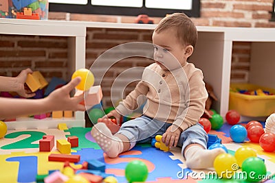 Adorable toddler playing with plastic construction blocks looking ball at kindergarten Stock Photo