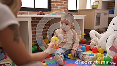 Adorable toddler playing with plastic construction blocks looking ball at kindergarten Stock Photo