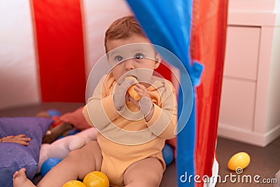 Adorable toddler sucking toy sitting on floor inside cirus tent at home Stock Photo