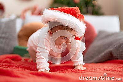 Adorable toddler wearing christmas hat crawling on sofa at home Stock Photo