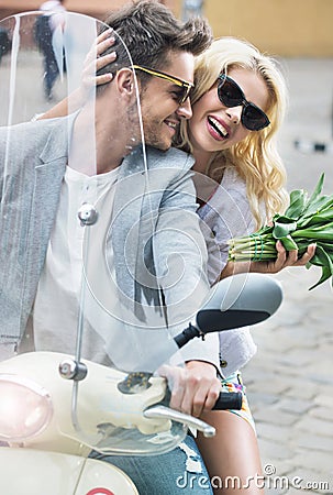 Adorable woman sitting on the scooter with her boyfriend Stock Photo