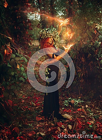 Adorable young redhair lady wizard conjures in the forest Stock Photo