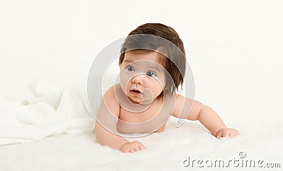 Adorably baby lie on towel in bed, white background. Happy childhood and healthcare concept. Yellow toned Stock Photo