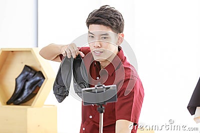 Adult asian man holding gimbal stabilizer with smartphone doing live to present sale product online via the internet Stock Photo