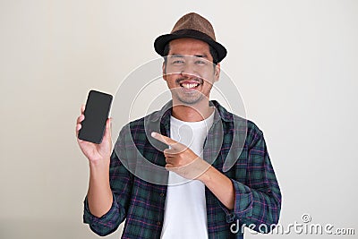 Adult Asian man smiling confident while showing blank mobile phone screen Stock Photo