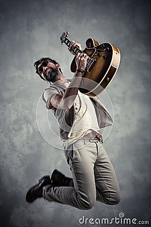 Adult caucasian guitarist portrait playing electric guitar and jumping on grunge background. Music singer modern concept Stock Photo