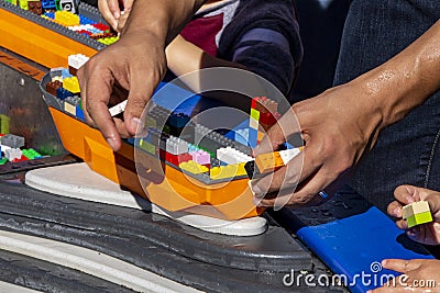 Adult and child hands building lego boats Editorial Stock Photo