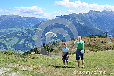 Adult and child looking to paraglider flying over beautiful mountains and valley. Editorial Stock Photo