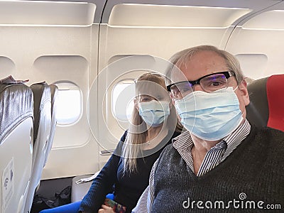 Adult couple taking a selfie while travelling by plane wearing a surgical mask during the covid pandemic Stock Photo
