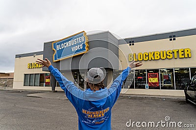 AUGUST 12 2018 - FAIRBANKS ALASKA: Female customer stands outside a Blockbuster Video rental store with arms out Editorial Stock Photo