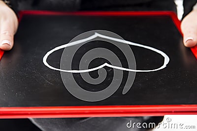 adult draws heart on the blackboard with white marker Stock Photo