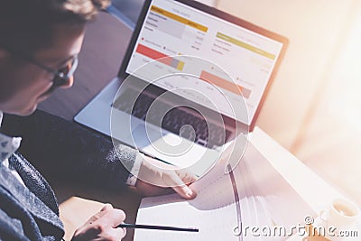 Adult elegant businessman in eyeglasses working at sunny office on laptop while sitting at wooden table.Coworker analyze Stock Photo