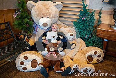 Adult female cuddles with a bunch of giant teddy bears Stock Photo