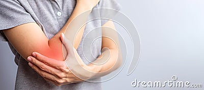 Adult female with her muscle pain on gray background. Woman having elbow ache due to lateral epicondylitis or tennis elbow. Stock Photo