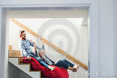 An adult hipster son and senior father indoors at home, having fun. Stock Photo
