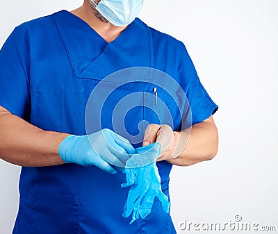 Adult male doctor in blue uniform puts on his hands blue sterile latex gloves Stock Photo