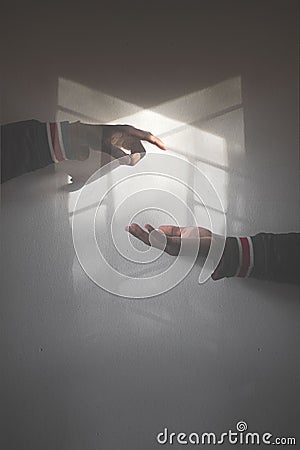 Adult male hands reaching out for each other in a room filled with natural sunlight Stock Photo