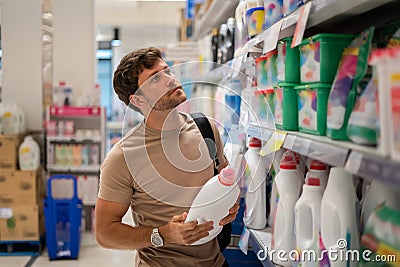 Male customer choosing detergent from shelf Stock Photo