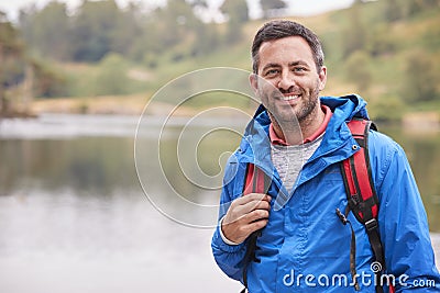 Adult man on a camping holiday standing by a lake smiling to camera, portrait, Lake District, UK Stock Photo