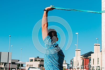 Adult man doing triceps and shoulder stretches in city park. Working trx outdoors, health and fitness concept Stock Photo