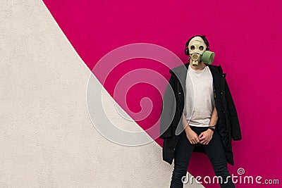 Adult man in gas mask hipster portrait trendy colors photography posing in black coat and white t-shirt on painted vivid pink Stock Photo